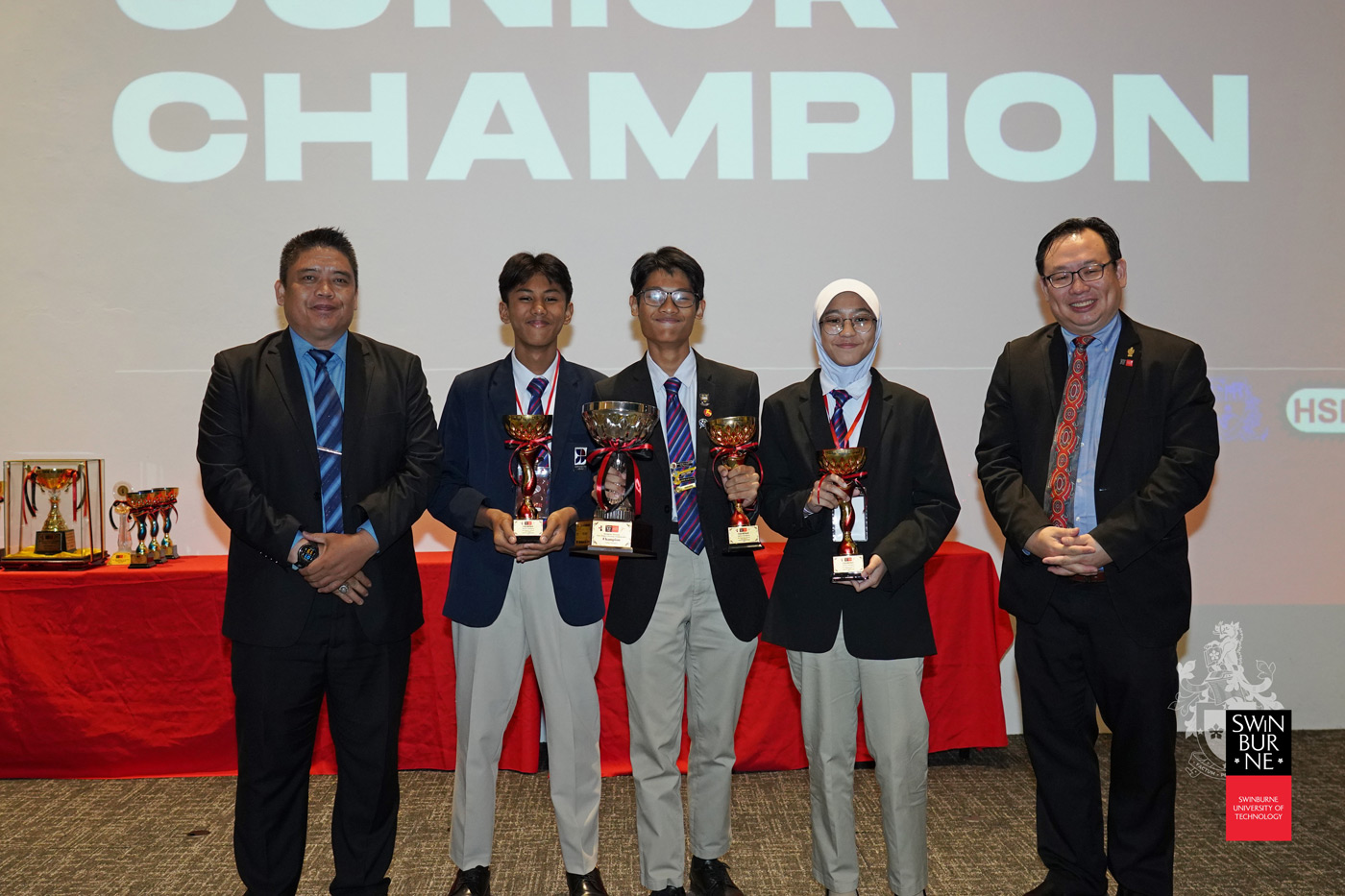 Junior champions (from second left) Jood Ammar bin Sazzli Shahlan, Badrul Ariff bin Badrul Akmal and Zara Aleesya binti Abdul Haizal with Mr Dennis Nur Amin Abdullah (left) and Ir Professor Lau Hieng Ho (right).