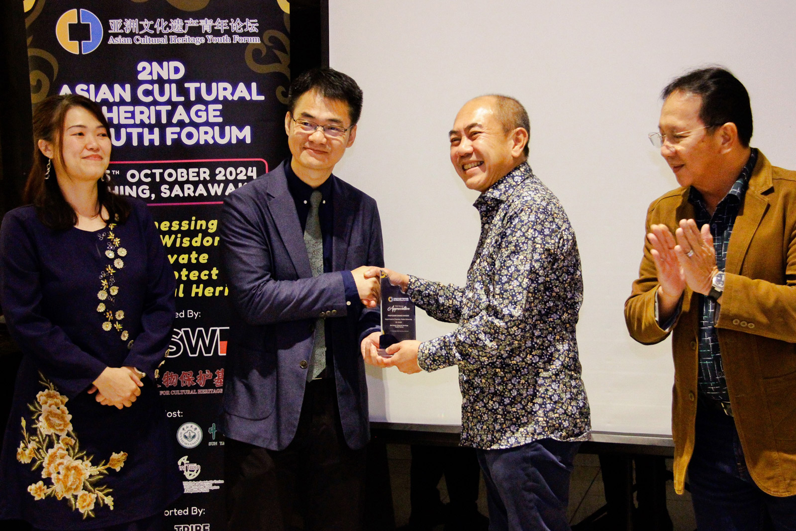 YB Dato Gerald Rentap Jabu (second right) and Professor Zhang ChaoZi (second left) exchange a token of appreciation as (from left) Dr Bibiana Lim and YB Tuan Haji Safiee bin Haji Ahmad look on.  